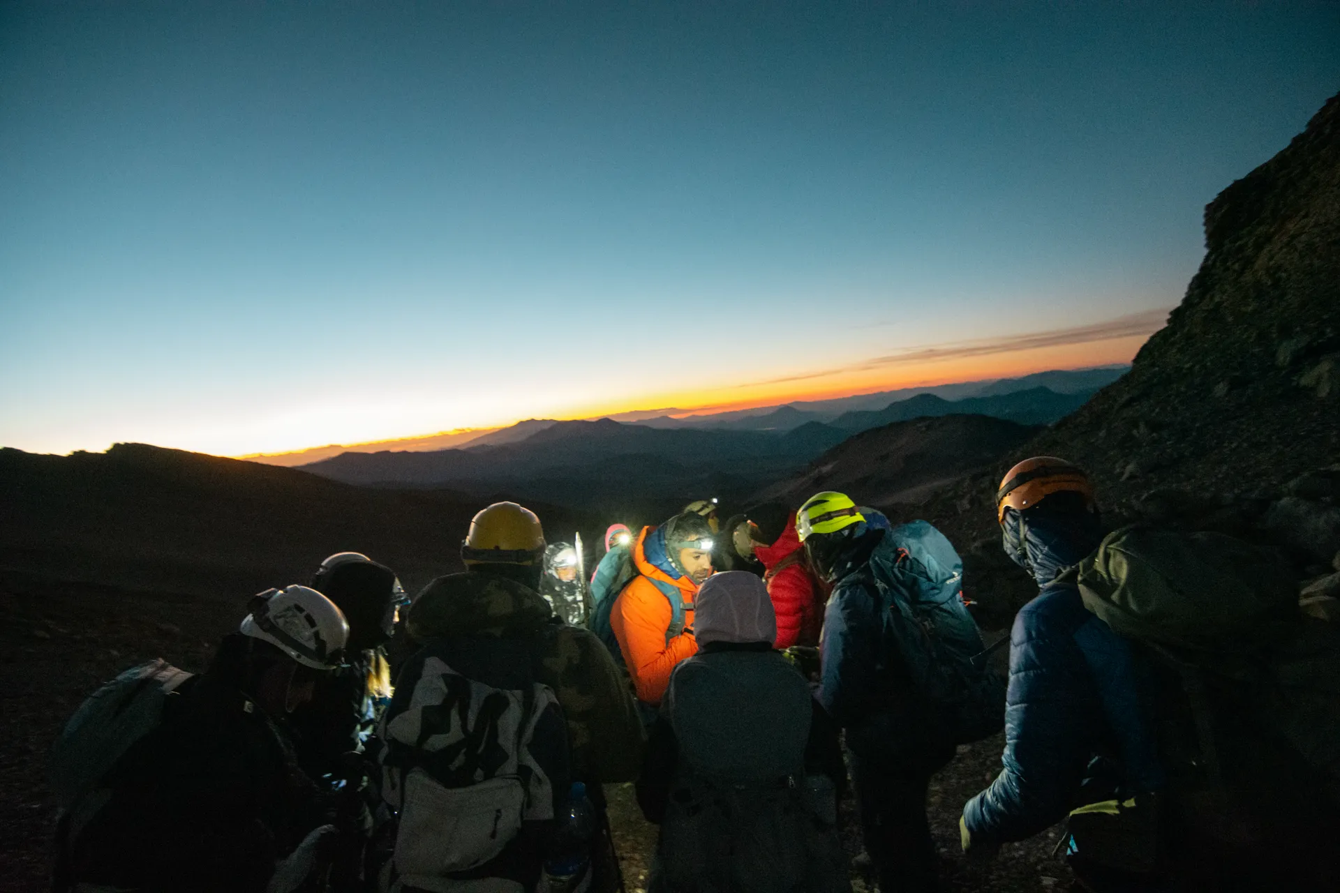 Grupo ascendiendo de madrugada con frontales al amanecer